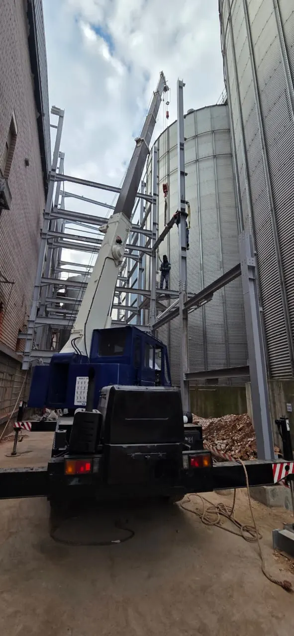 SteelBand Projects crane truck assisting with steel structure erection next to storage silos