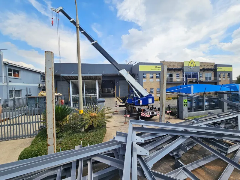 Crane truck lifting structural steel at a commercial building site