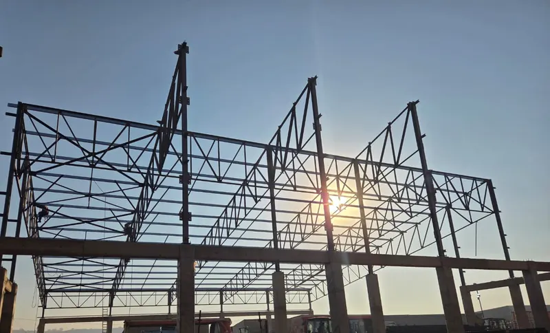 Structural steel truss frame for a warehouse building at sunset